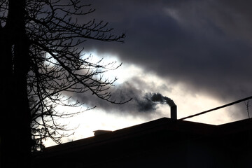 Trujący dym wylatuje z komina domu mieszkalnego. Piec na węgiel