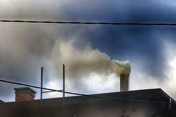 Trujący dym wylatuje z komina domu mieszkalnego. Piec na węgiel