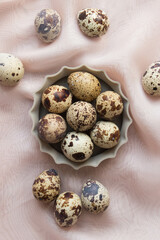 Raw fresh quail eggs in bowl. Top view.  Pink background.