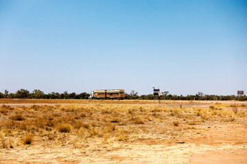 Road train and dry grass  in a flat dry desert landscape near Boulia in Outback Queensland, Australia