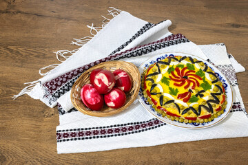 Traditional Romanian boeuf (beef) salad decorated and red Easter eggs with a traditional towel on a wooden table