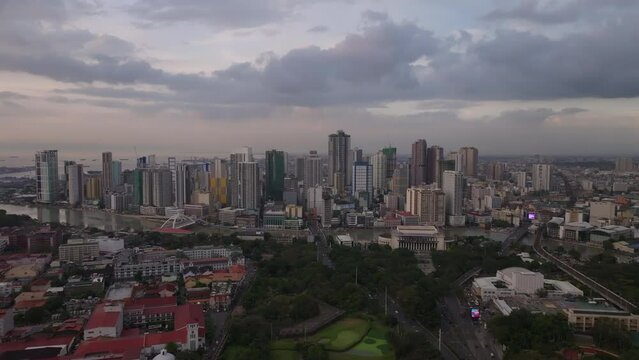 Aerial panoramic footage of high rise buildings in modern urban borough on riverbank. Clouds in twilight sky. Manila, Philippines