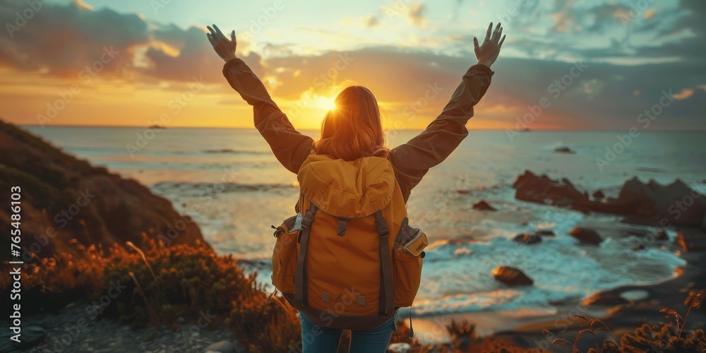 Wall mural confident woman with backpack with arms up relaxing at sunset seaside during a trip , traveler enjoy