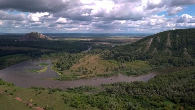 Aerial view of river amidst mountains and trees under cloudy sky