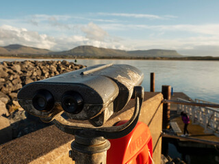 Viewing binoculars with stunning nature ocean and mountain scenery in the background. Cost of...