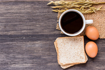 Ears of wheat and cup of coffee on a dark wooden table