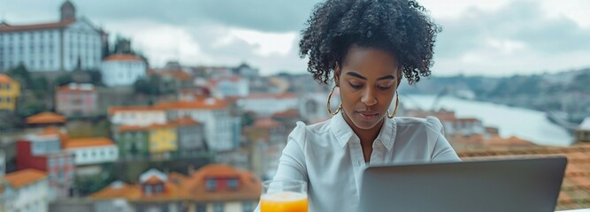 A captivating African American college student at a rooftop bar sipping a beverage on a gloomy metropolitan day while surfing her laptop - obrazy, fototapety, plakaty