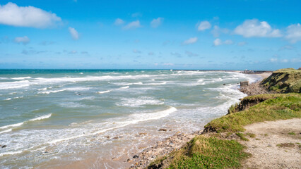 View of Denmark seashore, at North Sea sandy beach, summer sunny day with big waves and blue sky