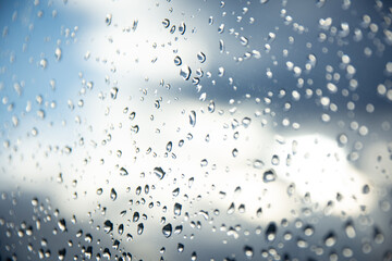 Kontrast der Elemente: Regentropfen an der Fensterscheibe vor sonnendurchflutetem Himmel - obrazy, fototapety, plakaty