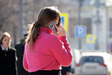 Woman talking on mobile phone on a city street in spring