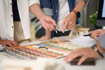 Group of designers of interior choosing material samples, working together at creative office