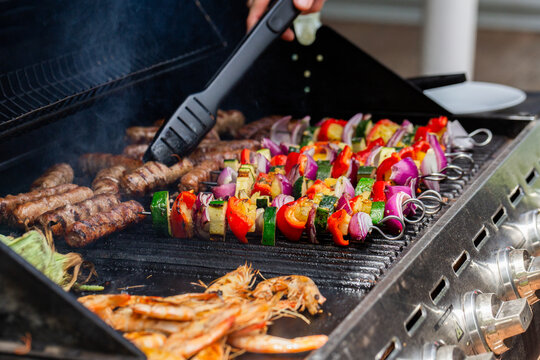 Kebabs, sausages, prawns and corn cooking together on bbq for lunch
