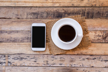 Cup of coffee with smart phone on a wooden table background.