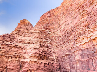 Angled view of a huge rock formation in the desert under the blue sky and hot sun