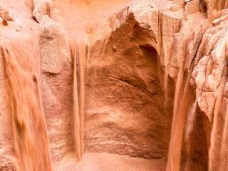 A sandy cave in the middle of the desert collapsing with sand flowing inside