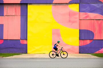Female Cyclist Riding by a Colourful Wall