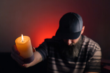 Bearded man holding a lit candle in his hand. Blue background
