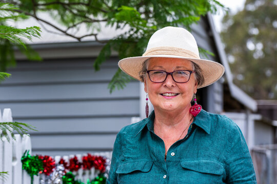 Senior woman in her sixties at Christmas standing beside white picket fence