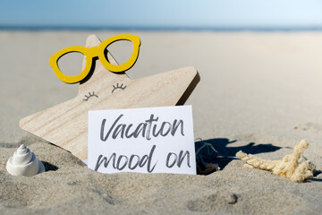 VACATION MOOD ON text on paper greeting card on background of beach chair lounge starfish summer...