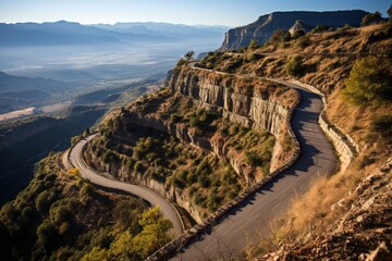 Scenic aerial view of winding serpentine road and sheer cliffs in the mountains at sunset