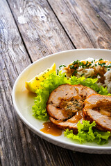 Stuffed turkey breast roulade with dried apricots and cranberries and boiled white rice on wooden table

