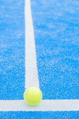 paddle tennis ball on the background line of a blue paddle tennis court