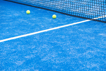 paddle tennis ball towards the net of a blue paddle tennis court