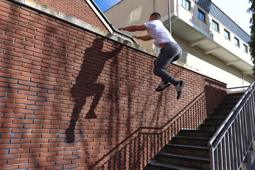 Caucasian man doing parkour jumping towards a wall with outstretched hands to fuck him. Concept of...