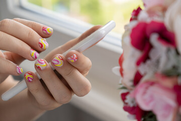 Woman manicured hands holding mobile phone, stylish summer colorful nails. Closeup of manicured...