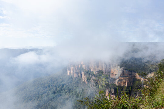 Mist and cloud mingled over rugged cliff face over valley