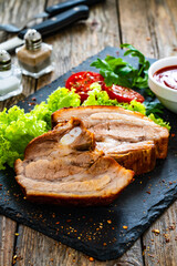 Tasty roast ribs and fresh vegetables on wooden table
