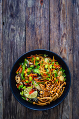 Asian style stir fried vegetables and noodles on wooden table
