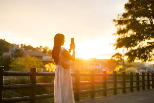 Woman use mobile phone to take photo under sunset in countryside