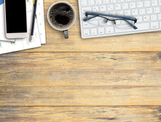 Wooden desk with Coffee cup,keyboard,smartphone,pencil and glasses