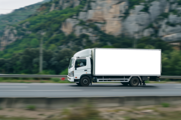 Panning photo, white box truck driving on the road with mockup space for advertising