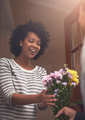 Happy, flowers and woman with man by door for anniversary or romantic gift at apartment. Smile, love and young female person receiving bouquet of pink floral plants for surprise at modern home.