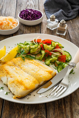 Seared halibut fillet and fresh vegetables on wooden table
