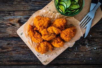 Fried breaded chicken nuggets served with fresh vegetables on wooden table
- 765591180