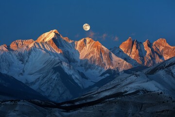 A full moon is seen rising above a silhouetted mountain range - obrazy, fototapety, plakaty