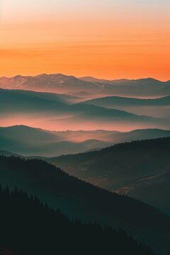 A stunning view of a mountain range bathed in the warm glow of the setting sun, casting long shadows and painting the sky with hues of orange and pink