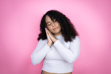 African american woman wearing casual sweater over pink background sleeping tired dreaming and...
