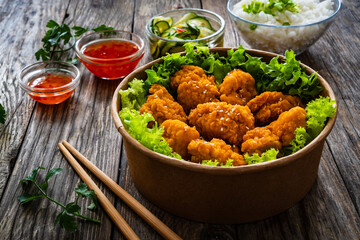Takeaway food - fried breaded chicken nuggets and vegetables on wooden table
- 765603173