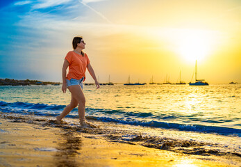 Beautiful mid-adult woman walking on sunny beach
