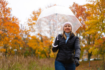 Healthy lifestyle - mid-adult woman walking in city park holding umbrella
- 765605503