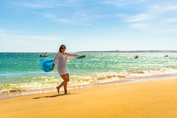 Beautiful woman walking on sunny beach holding shawl
- 765605570