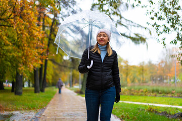 Healthy lifestyle - mid-adult woman walking in city park holding umbrella
- 765605765
