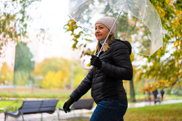 Healthy lifestyle - mid-adult woman walking in city park holding umbrella
- 765605907