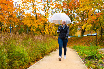 Healthy lifestyle - mid-adult woman walking in city park holding umbrella
- 765606108