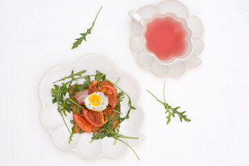  sandwiche with aragula, fried ham, tomatoes, fried egg, cup of berries tea on white background, top view.
