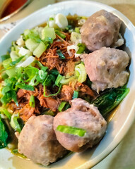 A bowl of traditional noodle called Mie Ayam Bakso taken from top angle. Top angle of Mie Ayam Bakso on a white bowl with meatball.